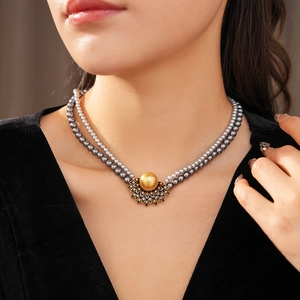 Detail of vintage double-layer dark grey pearl necklace with golden flower pendant charm