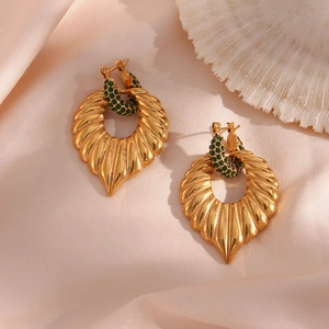 Detail of vintage gold earrings with green rhinestones on elegant silk background