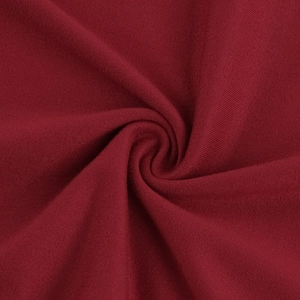 Détail macro du tricot rouge foncé montrant la texture plissée et le drapé en spirale