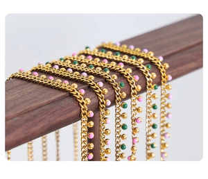 Detail of gold chain necklaces with colorful enamel bead tassels on wooden stand