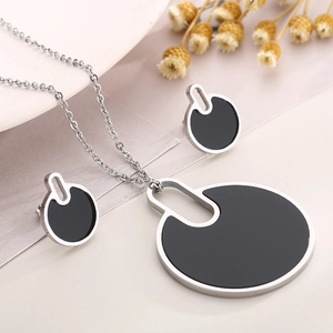 Detailed view of silver necklace and earrings set with black circular geometric pendants