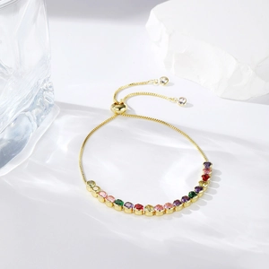 Close-up of golden adjustable slider bracelet with rainbow gradient cubic zirconia