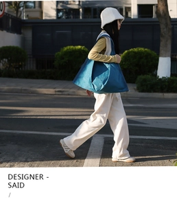 Street style view of a blue large capacity tote bag with unique geometric fold design
