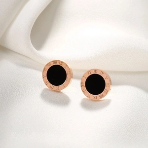 Detailed view of rose gold Roman numeral earrings with black inlay on silk fabric
