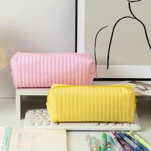 Close-up of pink and yellow large pencil cases with vertical stitched texture on desk