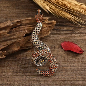 Detailed close-up of a vintage snake brooch with amber rhinestones on a rustic wood background