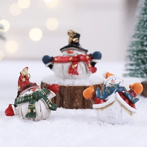 Three cute resin snowman figurines with hats and scarves in a cozy Christmas setting