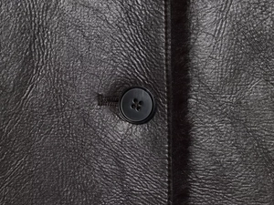Détail de la texture en similicuir noir avec coutures et fermeture à bouton