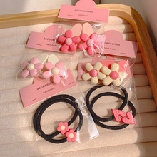 Detail of floral resin hair clips and heart elastic ties on pink cards in a beige tray