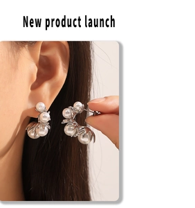Detailed view of silver-tone C-shaped hoop earrings with cluster pearls worn by a model