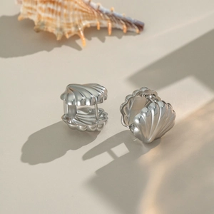 Textured silver seashell hoop earrings with nautical stripes on a beige background