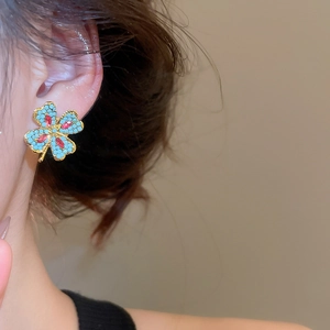 Close-up of elegant flower stud earrings with gold base and turquoise blue beads