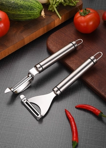 Close-up of dual stainless steel vegetable peelers set on a wooden kitchen board