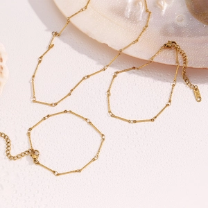 Detailed view of 18K gold plated stainless steel necklace and bracelet set on seashell