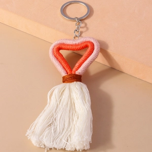 Macro shot of handmade woven heart keychain with cotton tassels and metal ring