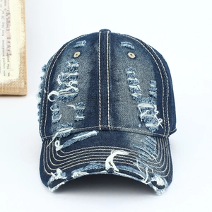 Detailed view of dark blue washed denim baseball cap with street style distressed holes