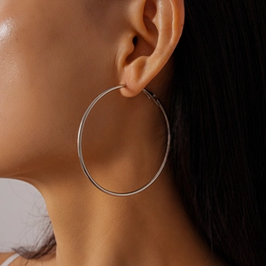 Close-up of oversized polished silver hoop earrings shown on model for size and fit