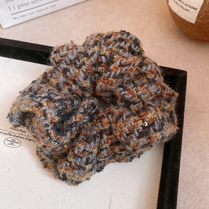 Détail d'un chouchou en tricot à carreaux gris brun avec de paillettes argentées