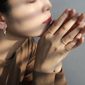Minimalist S925 sterling silver thin rings and twisted earring set on model with soft lighting