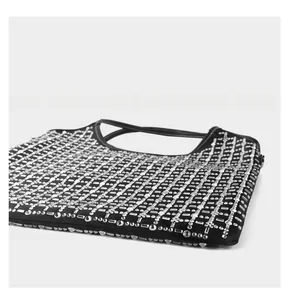 Close-up of black evening bag with silver rhinestone grid pattern and dual handles