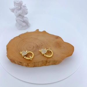 Detailed view of gold heart lobster clasps with micro-paved cubic zirconia on wood
