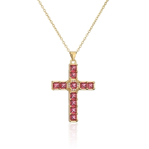 Macro detail of gold-plated cross necklace with red square zircons and clear gems