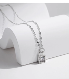 Macro detail of silver lock pendant with brilliant round-cut central moissanite stone