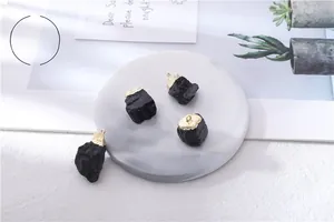 Macro shot of natural raw black tourmaline pendants with gold trim on marble