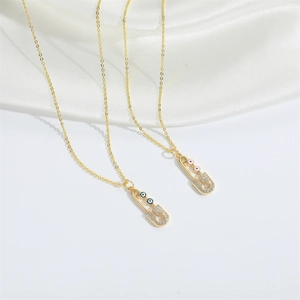 Detailed macro view of gold-plated safety pin pendants with evil eye and zircons