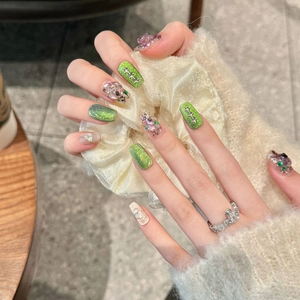 Handmade press-on nails with colorful sequins, glitter, and crystals on a model hand