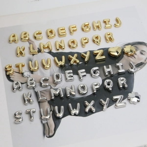 Close-up of gold and silver bubble letter charms with heart and clover metal shapes