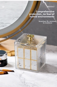 Detail of transparent acrylic makeup organizer with gold floral handle and vertical stripes