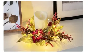 Detail of Christmas candle ring with red berries, LED candle and warm string lights