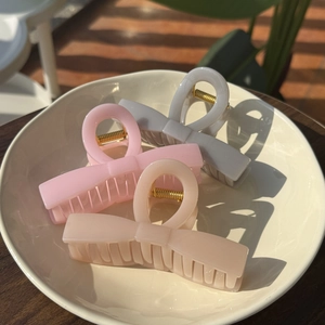Drei elegante Haarspangen in Schleifenform in Pastelltönen auf einer Keramikplatte