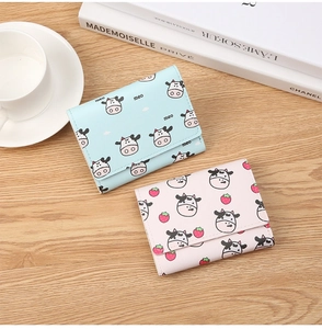 Three-fold mini wallets with cow pattern in light blue and pink on wooden table