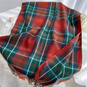 Detailed close-up of soft red and green plaid scarf with decorative fringe texture