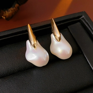 Detailed close-up of Baroque irregular pearl earrings with gold plating on black leather