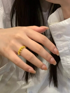 Detailed close-up of a golden flower crown ring on finger with elegant tassel beads