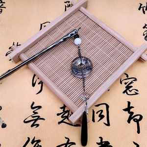 Detail view of a vintage metal hairpin with lotus charm and tassels on a bamboo tray