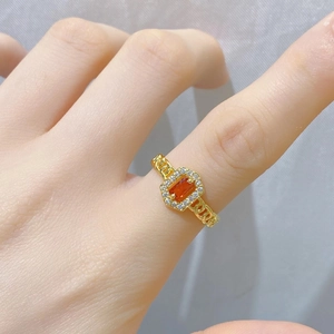 Nahaufnahme eines Goldrings mit orangefarbenem Edelstein und Diamanten am Kettenglied