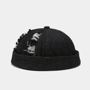 Close-up of black denim docker cap featuring vintage distressed ripped hole details