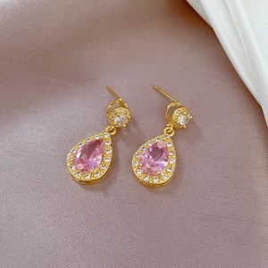 Macro shot of gold-plated teardrop earrings with pink zircon and micro-pave crystals