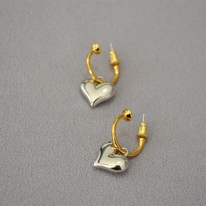 Detailed view of bicolor heart-shaped drop earrings with high-polish metallic finish