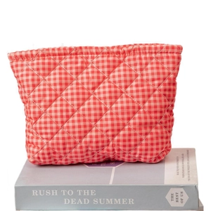 Red gingham quilted cosmetic bag for women on books with soft vintage floral aesthetic