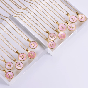 Close-up of golden alphabet pendants A-N with pink shell inlay on crystal stands