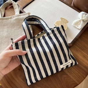 Detailed close-up of a striped canvas handbag with a zipper and Simple Wish logo