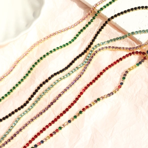 Close-up of colorful zircon tennis necklaces on a light beige pleated paper background