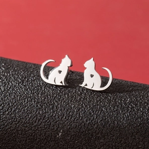 Macro view of silver cat stud earrings with hollow heart detail on black leather stand