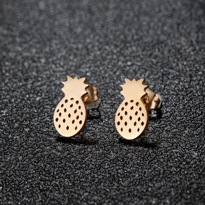 Cute pineapple stud earrings in gold tone with hollow texture on a dark surface
