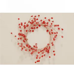 Festive red berry candle ring with metallic wire base on a textured surface